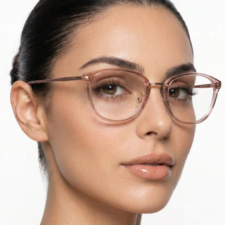 A woman with smooth skin and nude lipstick wears EyeCandys Posh Square unisex rectangular glasses in transparent pink, her dark hair pulled back as she looks confidently at the camera against a plain white background.