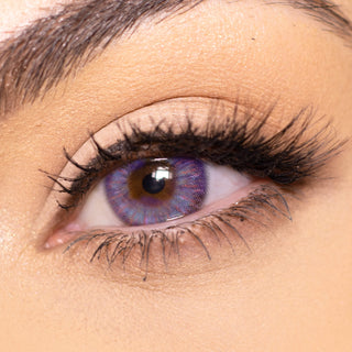 Close-up shot of a model eye wearing multi-tone Grey Violet colored contact lens in one eye that is naturally dark-brown with natural eye make up