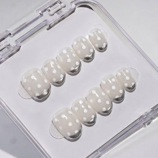 EyeCandys Silver Spotted Press-On Nails feature a light beige base with white polka dots, neatly arranged in two rows inside a clear case for an easy salon-gel manicure at home.