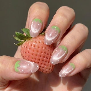 Hand wearing EyeCandys Strawbelina press on nails featuring pink strawberry nails with white dots and green tip accents.
