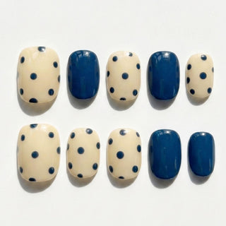 Short oval press on nails EyeCandys Sunny Side Up with butter yellow base, navy polka dot pattern, and solid navy accent nails.