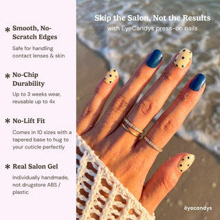 Stylish hand wearing EyeCandys Sunny Side Up press on nails featuring butter yellow polka dot nails and glossy navy accent nails.