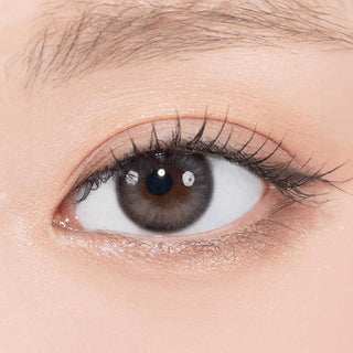 Close-up shot of model's eye adorned with Gemhour Theia Glow Black color contact lenses with prescription, complemented by minimalist eye makeup, showing the brightening and enlarging effect of the circle contact lens on dark brown eyes.