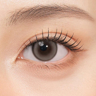 Close-up shot of model's eye adorned with Gemhour Themis Nude Grey color contact lenses with prescription, complemented by minimalist eye makeup, showing the brightening and enlarging effect of the circle contact lens on dark brown eyes.