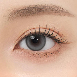 Close-up shot of model's eye adorned with Gemhour Themis Sage Grey color contact lenses with prescription, complemented by minimalist eye makeup, showing the brightening and enlarging effect of the circle contact lens on dark brown eyes.