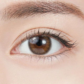 Close-up shot of model's eye adorned with Topards 1-Day Garnet Brown (10pk) daily color contact lenses with prescription, complemented by minimalist eye makeup, showing the brightening and enlarging effect of the circle contact lens on dark brown eyes.