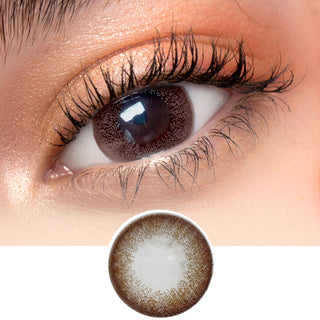 Close-up image featuring a model wearing Toronto Grey contact lenses over dark brown irises, complemented by naturally curled lashes and peach eyeshadow.