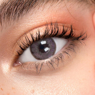 Close up shot of a model with natural dark eyes wearing EyeCandys Pink Label Angel Pink colored contact lens complemented by natural eye make up