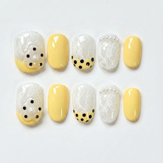 EyeCandys Bananito press on nails with banana yellow base, sheer lace nails, rhinestones, and polka dot tip design for bright spring nails.