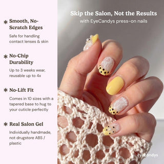 Close up hand showcasing EyeCandys Bananito press on nails with banana yellow nails, lace design, and black polka dot tips.