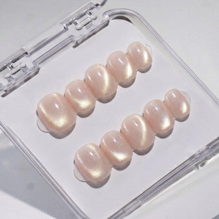 EyeCandys Bare Minimum press on nails featuring warm nude peach cat-eye nails with iridescent gold shimmer and glossy finish in a short round shape.