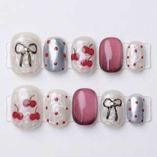 EyeCandys Cherry Bomb press on nails with sculpted cherries, chrome cat eye details, red polka dots, and gold bow accent design.