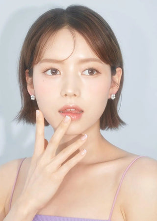 Asian model demonstrating a K-idol-inspired look with Chuu Milk & Tea Cream Grey coloured contact lenses, highlighting the instant brightening and enlarging effect of the circle contact lenses over dark irises.