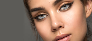 Female model wearing Shade Blue blended color contacts, showing the transformative effect of the lens on her dark eyes, on a grey background