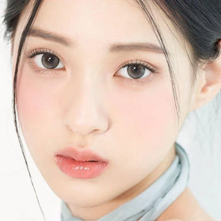 Asian model demonstrating a K-idol-inspired look with 1-Day Pebble Grey coloured contact lenses, highlighting the instant brightening and enlarging effect of the circle contact lenses over dark irises.