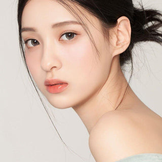 Asian model demonstrating a K-idol-inspired look with 1-Day Pebble Grey coloured contact lenses, highlighting the instant brightening and enlarging effect of the circle contact lenses over dark irises.