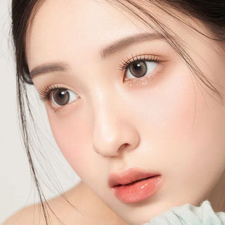 Asian model demonstrating a K-idol-inspired look with 1-Day Pebble Grey coloured contact lenses, highlighting the instant brightening and enlarging effect of the circle contact lenses over dark irises.