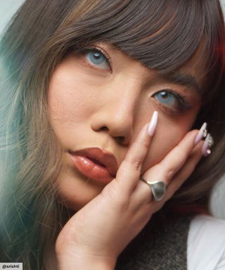 A female model with natural dark eyes wearing eyecandys dare to be blue contact lenses, complemented by pink eyeshadow and peach lipstick