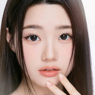 Model with natural makeup and long lashes wearing EyeCandys I-Girl One Pick Natural Gray contact lenses