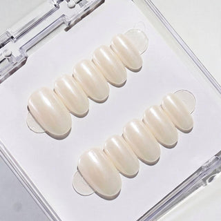 Close-up of Eyecandys Soft Serve reusable press-on nails showcasing a glossy pearl white chrome finish with creamy ivory and milky white tones.