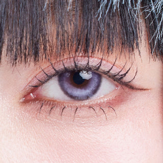 Close-up shot of model's eye adorned with Dollring Poppy Violet prescription circle contact lenses, complemented by clean eye makeup, showing the brightening effect of the prescription cosmetic contact lens on dark brown eyes.