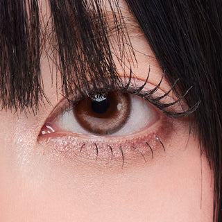Close-up shot of model's eye adorned with Zoe Brown prescription circle contact lenses, complemented by clean eye makeup, showing the brightening effect of the prescription cosmetic contact lens on dark brown eyes.