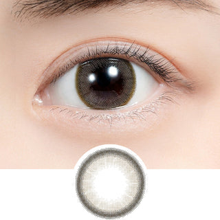 Close-up shot of model's eye adorned with Feliamo 1-Day Airy Beige (10pk) daily color contact lenses with prescription, paired with clean-girl eye makeup, showing the brightening and enlarging effect of the circle contact lens on dark brown eyes, above a cutout of the contact lens with limbal ring on a white background.