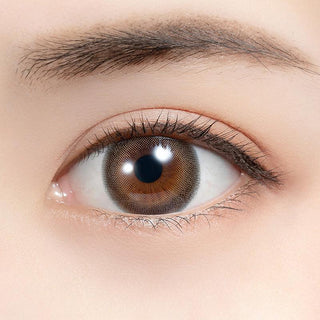 Close-up shot of model's eye adorned with Feliamo 1-Day Affogato (10pk) color contact lenses with prescription, complemented by minimalist eye makeup, showing the brightening and enlarging effect of the circle contact lens on dark brown eyes.