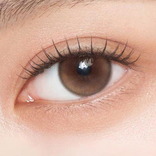 Close-up shot of model's eye adorned with Gemhour Demeter 1-Day Amber Brown (10pk) color contact lenses with prescription, complemented by minimalist eye makeup, showing the brightening and enlarging effect of the circle contact lens on dark brown eyes.