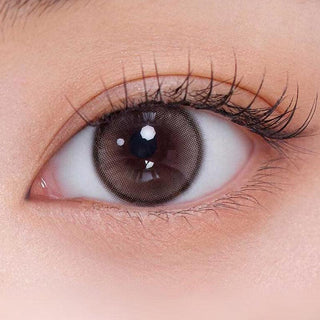 Close-up shot of model's eye adorned with Gemhour Demeter 1-Day Ash Choco (10pk) color contact lenses with prescription, complemented by minimalist eye makeup, showing the brightening and enlarging effect of the circle contact lens on dark brown eyes.