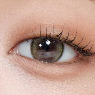Close-up shot of model's eye adorned with Gemhour Demeter 1-Day Olive Green (10pk) color contact lenses with prescription, complemented by minimalist eye makeup, showing the brightening and enlarging effect of the circle contact lens on dark brown eyes.