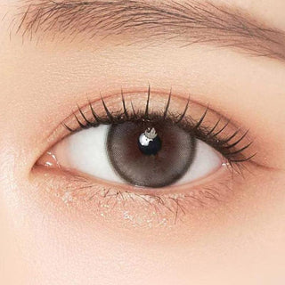 Close-up shot of model's eye adorned with Gemhour Demeter 1-Day Pebble Grey (10pk) color contact lenses with prescription, complemented by minimalist eye makeup, showing the brightening and enlarging effect of the circle contact lens on dark brown eyes.