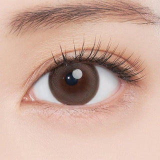 Close-up shot of model's eye adorned with Gemhour Freyja 1-Day Mood Brown (10pk) color contact lenses with prescription, complemented by minimalist eye makeup, showing the brightening and enlarging effect of the circle contact lens on dark brown eyes.