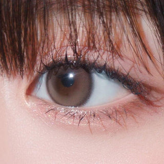 Close-up shot of model's eye adorned with Gemhour Hecate 1-Day Sand Brown (10pk) color contact lenses with prescription, complemented by minimalist eye makeup, showing the brightening and enlarging effect of the circle contact lens on dark brown eyes.