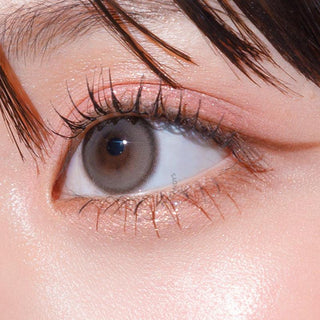 Close-up shot of model's eye adorned with Gemhour Hecate 1-Day Taupe Grey (10pk) color contact lenses with prescription, complemented by minimalist eye makeup, showing the brightening and enlarging effect of the circle contact lens on dark brown eyes.