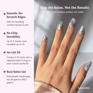 Hand wearing reusable Gilded Cirrus press on nails with impressionist sky blue cloud art, gold celestial details, and elegant short oval shape.
