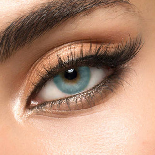 Close-up shot of a model with natural dark eyes wearing glossy blue contact lenses, complemented by natural eye make up. Close-up image showcases the model's eyes adorned with the same blue contact lenses.