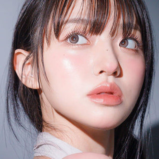 Asian model demonstrating a K-idol-inspired look with 1-Day Taupe Grey coloured contact lenses, highlighting the instant brightening and enlarging effect of the circle contact lenses over dark irises.