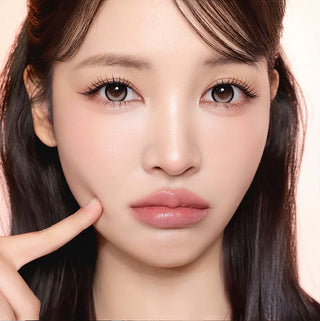 Model with natural makeup and long lashes wearing EyeCandys i-Sha Dekame Kiss Me Milky Choco brown colored contact lenses
