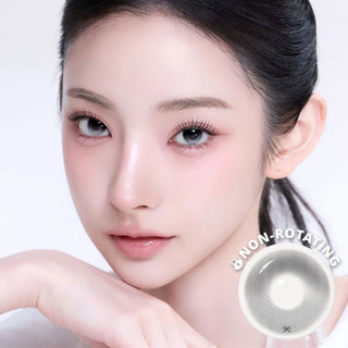 Close-up beauty portrait of a woman wearing grey contact lenses, with soft pink makeup.