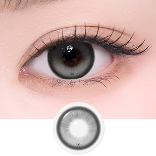 Close-up of an eye with long lashes wearing EyeCandys i-SHA Reborn Red 1-Day Milky Gray (10pk) colored contact lenses, with the lens design displayed below. Features a soft milky gray pattern with subtle depth for a natural, bright-eyed look in a comfortable silicone hydrogel daily lens.