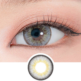 Close-up shot of a model's eye wearing Lensrang Iwwitch Up Grey color contacts with prescription, paired with K-beauty-inspired eye makeup, showing the brightening and enlarging effect of the circle contact lens on dark brown eyes, above a cutout of the contact lens pattern with limbal ring on a white background.