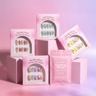 Four boxes of EyeCandys' The Short Oval Edit Press-On Nail Set and a pink package labeled "insanely sticky" are displayed on pastel pink blocks against a pink background. Each box showcases different short oval designs, providing a salon-quality gel manicure look right at home.