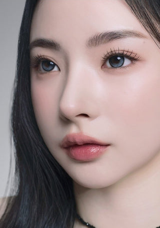 A female model with natural dark eyes wearing i-Sha Reborn Moon Stone contact lenses