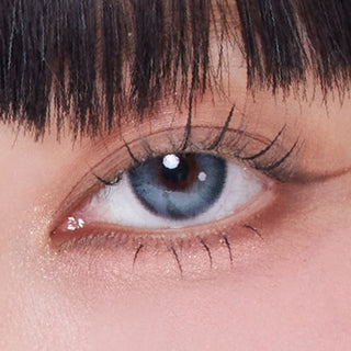 Close-up shot of model's eye adorned with Eyesm Hugmoon Muse Blue prescription colored contacts, complemented by clean eye makeup, showing the brightening effect of the prescription cosmetic contact lens on dark brown eyes.