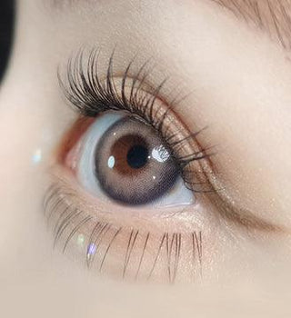 Macro shot of an eye wearing the Olola Torrid Love Beige (KR) prescription colour contact lens, showing the multi-colored detail and natural effect on dark brown eyes.
