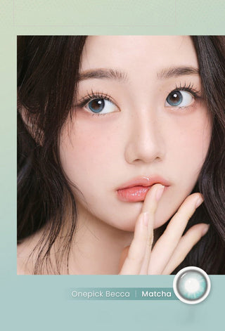 A woman with fair skin and long dark hair gazes upward, her finger near her lips, wearing i-Girl One Pick Becca Matcha Blue contacts for a natural look. Text reads "i-Girl One Pick Becca Matcha Blue" beside an image of a contact lens.