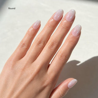 Hand wearing reusable EyeCandys Glazed Donut press on nails featuring soft pink to milky white gradient and glossy glazed finish.
