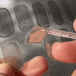 Step three of applying EyeCandys Gel Nail Stickers: peeling the sticker from the strip and applying it to the nail for a smooth, salon-quality gel manicure