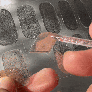 Step three of applying EyeCandys Gel Nail Stickers: peeling the sticker from the strip and applying it to the nail for a smooth, salon-quality gel manicure